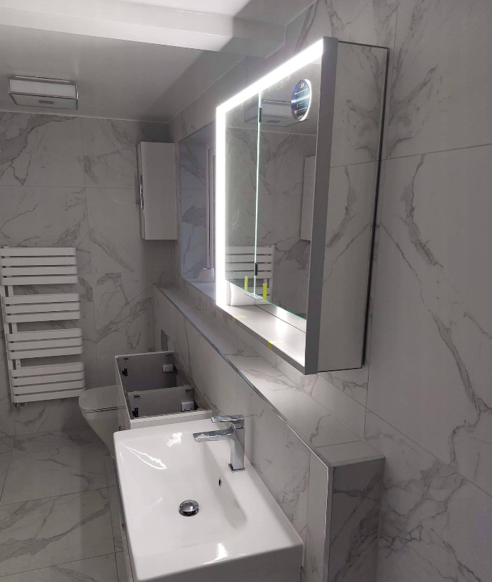 Contemporary bathroom installation with tiled walls and mirror lighting